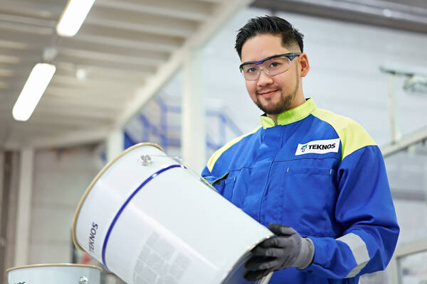 Teknos expert wearing safety gear working with paint testing equipment in an industrial setting.