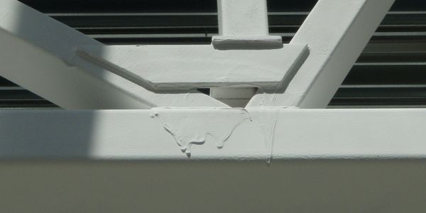 Close-up of a white painted metal structure with visible paint drips.